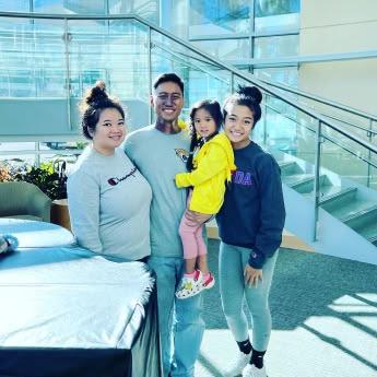 Patrick Palompo, his wife and daughters stand in the main lobby of the UF Health Proton Therapy Institute after he completed treatment for cancer of the head and neck.
