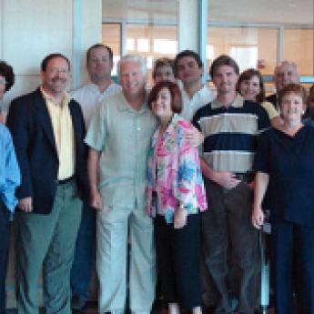 Group of men and women standing in a room with a glass wall in the background